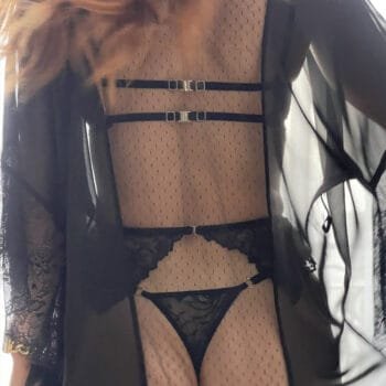 Femme de dos en ensemble lingerie coquin noir en dentelle avec porte-jarretelles.